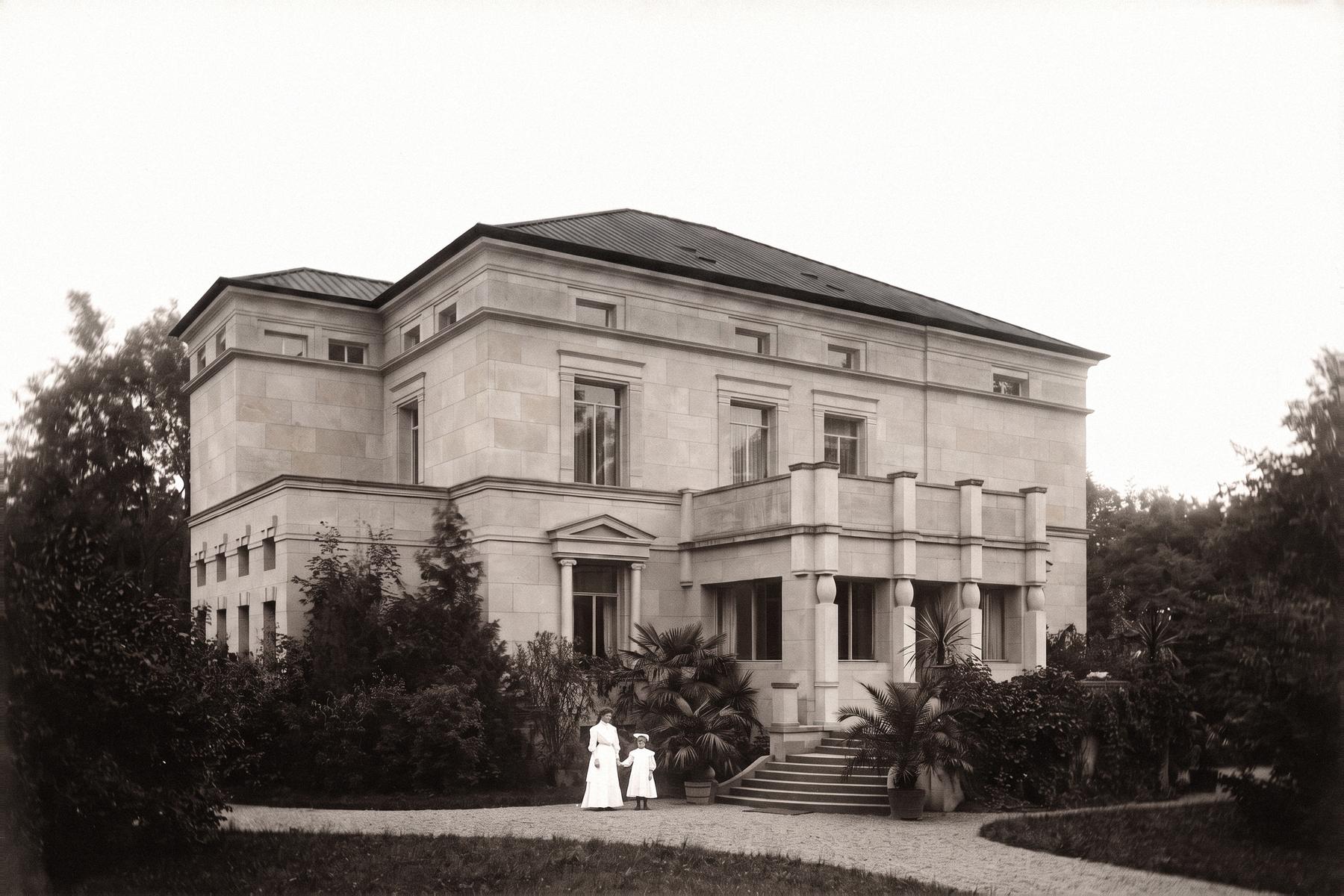 Die Villa Soennecken in einer historischen Ansicht mit Palmen vor der Freitreppe und zwei Personen auf dem Kiesweg, Illustration